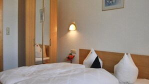 Une chambre d’hôtel avec un lit, une tête de lit en bois, une table de chevet avec une lampe et un miroir.