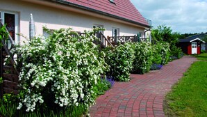 A house with a red roof, white exterior walls, and a brick pathway leading to the entrance. - Reihenhaus mit Wlan in Buchholz am Muritzsee (Buchholz)