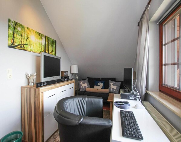A compact room with a desk, a chair, a sofa, a TV, and a painting on the wall. - Apartment in Bad Sachsa Near Harz Mountains (Bad Sachsa)