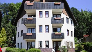 Un edificio de varios pisos con balcones, techo inclinado y base de ladrillo.