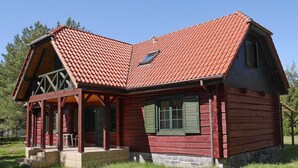 Eine Blockhütte mit rotem Ziegeldach, einer Veranda und einem kleinen Fenster.