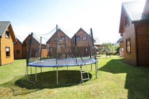 A residential area with wooden houses, a trampoline in the yard, and a swing set. - Terraced House in Rewal Near Sandy Beach (Rewal)