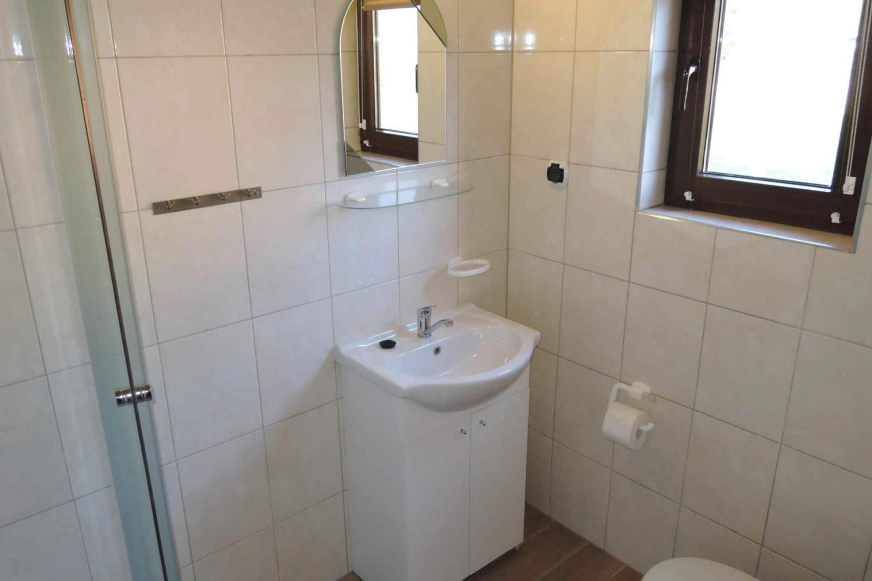 A bathroom with a white sink, mirror, and toilet.