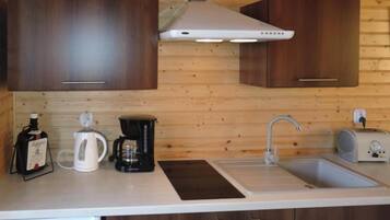 A compact kitchen with wooden cabinets, a coffee maker, a kettle, and a toaster.