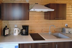 Una cocina funcional con muebles de madera, cafetera, hervidor y tostadora.