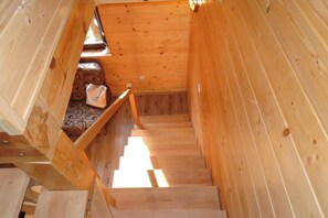 A wooden staircase leading to a room with a patterned sofa. - Terraced House in Rewal Near Sandy Beach (Rewal)