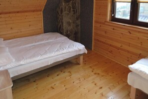 A small, single-bed room with wooden walls and a stone accent wall. - Terraced House in Rewal Near Sandy Beach (Rewal)
