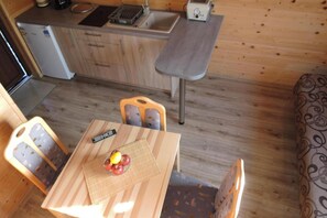 A compact kitchen with a sink, a toaster, and a refrigerator. There is a dining table with chairs and a remote control on it. - Terraced House in Rewal Near Sandy Beach (Rewal)