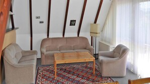 Un salon comprenant un canapé, deux fauteuils, une table basse en bois et un tapis à motifs.