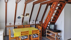 Une pièce chaleureuse avec une table en bois, des chaises, un téléviseur et une bibliothèque.