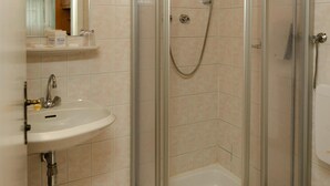 Een badkamer met wastafel, toilet en douchecabine.