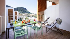 A balcony with a dining table set for breakfast, chairs, and a hammock. - Residence Olivo, Garda (Garda)