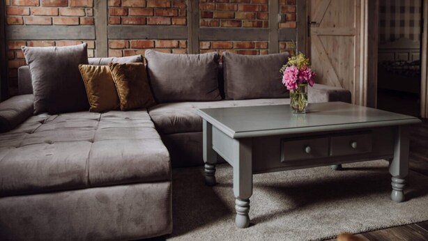 A sectional sofa with a glass coffee table, a brick wall, and a wooden door. - Apartment in Gronowo Near Lake Siecino (Zlocieniec)