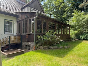 A traditional wooden house with a stone fireplace, a wooden porch, and a stone bench. - Ferienhaus, Schorfheide (Schorfheide)
