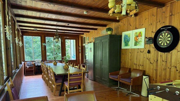 A wooden interior with a dining area, seating, a dartboard, and a foosball table. - Ferienhaus, Schorfheide (Schorfheide)