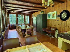 Puinen sisustus, jossa on ruokailutila, istuimia, tikanheittoalusta ja pöytäjalkapallopeli.
