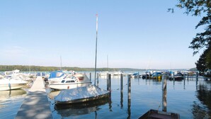 A marina with several boats docked, a covered boat in the foreground, and a clear sky. - Ferienhaus, Schorfheide (Schorfheide)