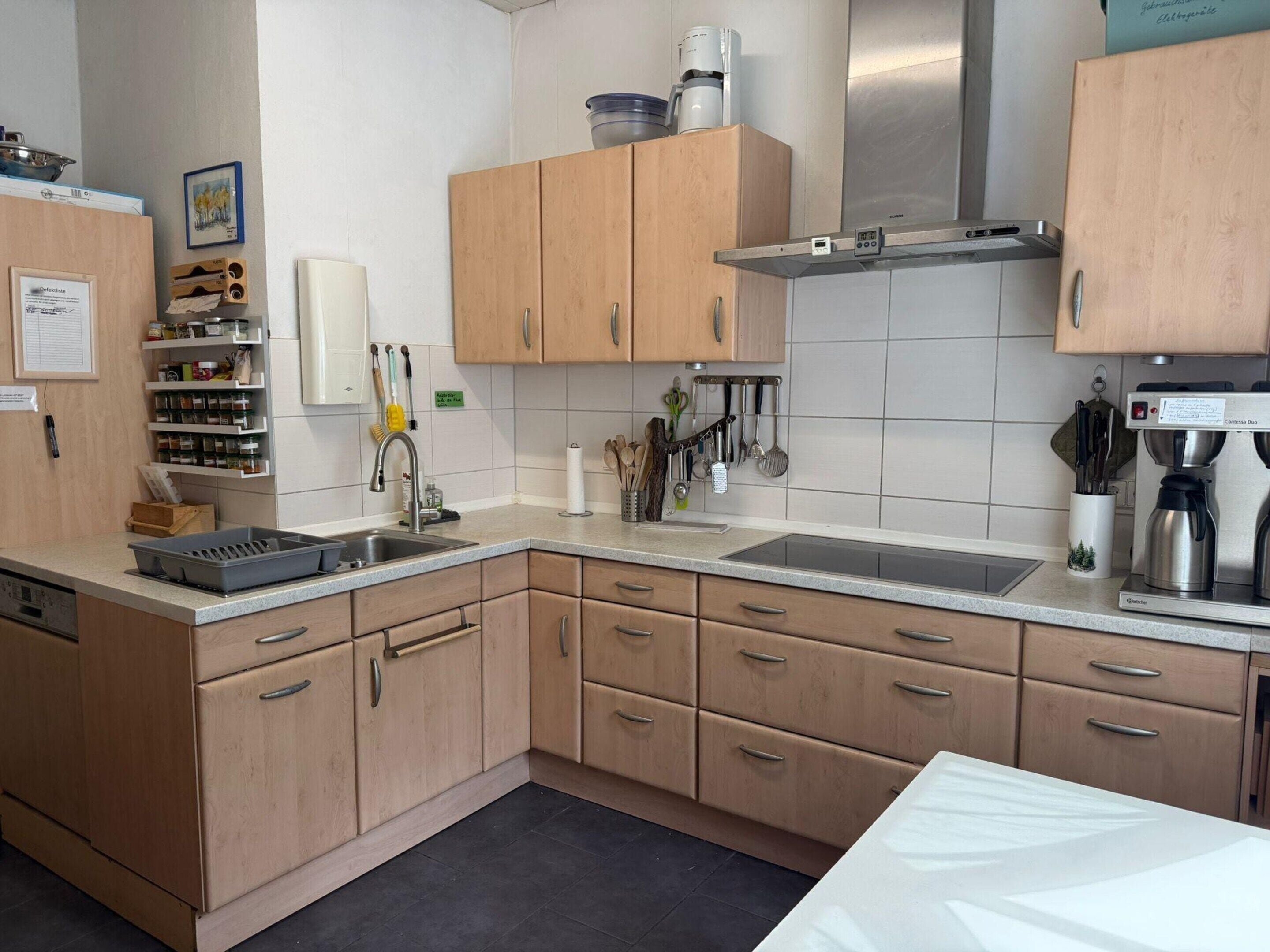 A kitchen with wooden cabinets, a stainless steel sink, and a coffee machine.