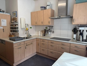A kitchen with wooden cabinets, a stainless steel sink, and a coffee machine. - Ferienhaus, Schorfheide (Schorfheide)