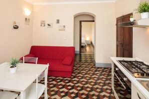 A compact kitchen with a red sofa, a dining table, and a patterned floor. - Lovely Holiday Flat With Shared Pool in Lerici (Lerici)