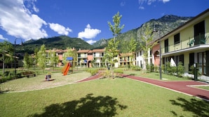 A courtyard with a playground, a red running track, and buildings with balconies. - Apartment in Porlezza With Lake View (Porlezza)
