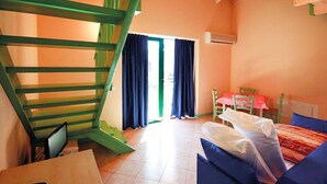 A room with a bed, a desk, a chair, a staircase, and a window with curtains. - Residence Oasi del Viandante in Dervio (Dervio)