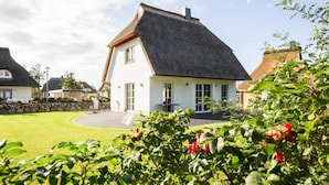 A house with a steeply pitched roof, white exterior walls, and a stone foundation. - Ferienhaus, Fuhlendorf (Fuhlendorf)