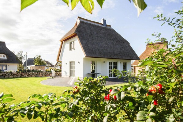Ein Haus mit einem steilen Dach, weißen Außenwänden und einem Steinfundament.