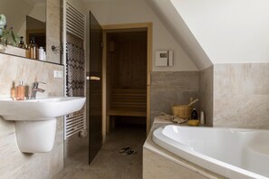 Ein modernes Badezimmer mit einer großen Badewanne, einem Waschbecken mit Pflegeprodukten und einer Duschkabine.
