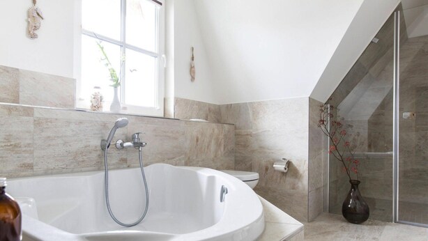 Een moderne badkamer met een vrijstaand bad, een glazen douchecabine en een marmeren vloer.
