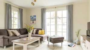 A modern living room with a sectional sofa, a coffee table, and a TV stand. - Ferienhaus, Fuhlendorf (Fuhlendorf)