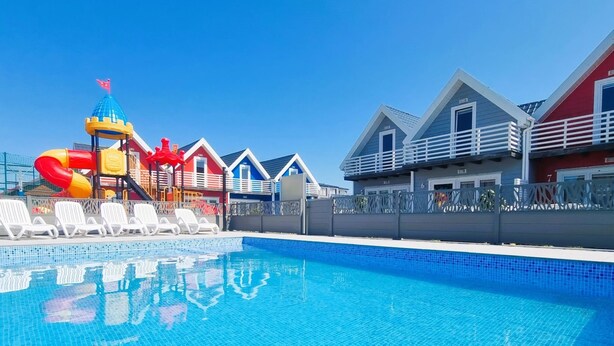 A swimming pool with a water slide and lounge chairs. - Single-story Holiday Homes, Pool, Playground (Mielno)