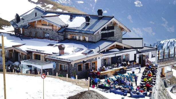 A hotel with a stone facade, wooden interior, and a sign reading "WEDELHÖTTE".