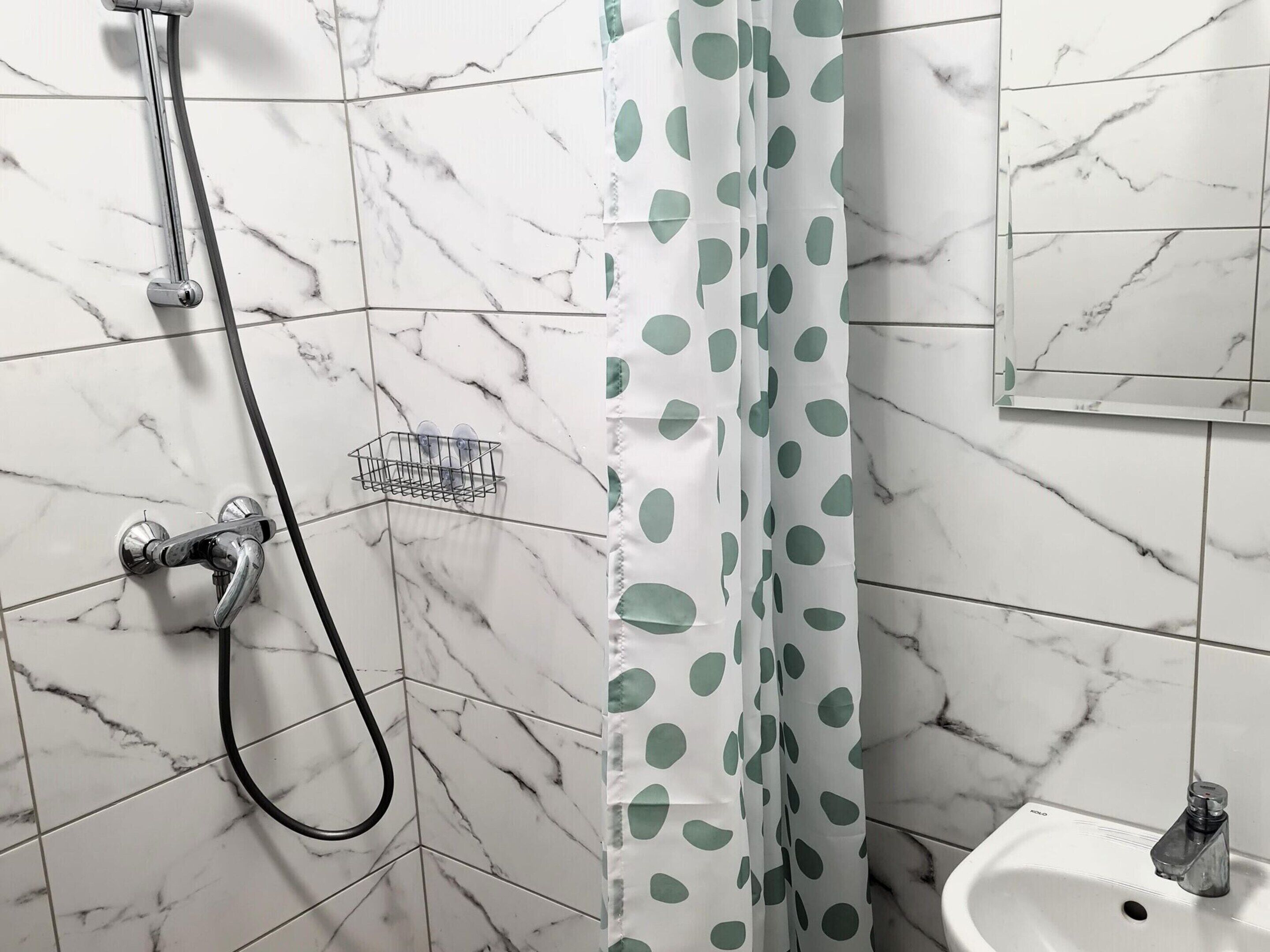 A bathroom with a shower, a sink, and a mirror.