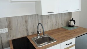Una cocina moderna con armarios blancos, un lavamanos de acero inoxidable y una encimera de madera.