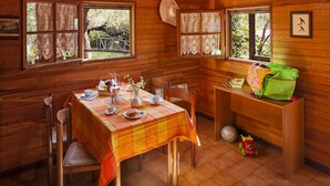 A wooden cabin dining area with a table set for two, a window with lace curtains, and a hat on the wall. - Holiday Village Caravelle Camping Vill, Ceriale (Ceriale)