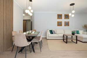 A modern living room with a dining area, featuring a sofa, coffee table, and a dining table with chairs. - Spacious Apartment,summer Swimming Pool, Pobierowo (Rewal)
