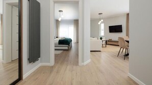 A modern living room with a sofa, a dining area with a table and chairs, and a bedroom with a bed and a window. - Spacious Apartment,summer Swimming Pool, Pobierowo (Rewal)