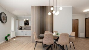 A modern dining area with a striped partition, a round table, and six chairs. - Spacious Apartment,summer Swimming Pool, Pobierowo (Rewal)
