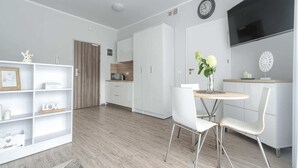 A modern, well-lit room with a dining area, kitchenette, and a TV mounted on the wall. - Apartment in Pobierowo Near Baltic Beach (Rewal)