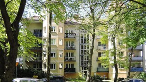 A multi-story residential building with balconies, parked cars, and surrounding trees. - Holiday Flat in Miedzyzdroje, top Location for 4 Persons (Miedzyzdroje)