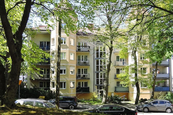A multi-story residential building with balconies, parked cars, and surrounding trees. - Holiday Flat in Miedzyzdroje, top Location for 4 Persons (Miedzyzdroje)