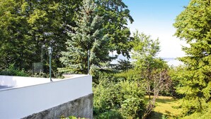 Un edificio moderno con facciata bianca, immerso nel verde e circondato da alberi.