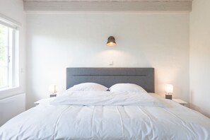 A neatly made bed with white linens, a grey headboard, and two bedside lamps. - Stylische Ferienwohnung in Landlicher Idylle (Wobbenbüll)