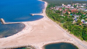 Ein Luftbild einer Küstenstadt mit Strand, einem Steg und einer Mischung aus Wohn- und Geschäftshäusern.