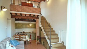 Ein Wohnzimmer mit einer Couch, einem Essbereich und einer Treppe zu einer oberen Ebene.