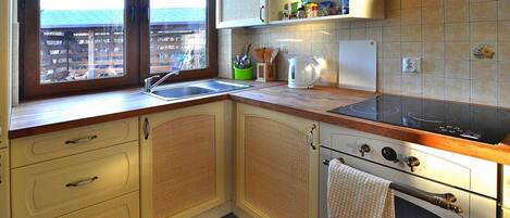 A kitchen with a window, a stove, and cabinets.