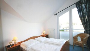 Une chambre d’hôtel avec un lit, deux tables de chevet avec des lampes, une chaise et une vue sur l’extérieur.