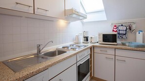 Une cuisine moderne avec des armoires blanches, un comptoir en granit, un four encastré, un four à micro-ondes et une machine à café.