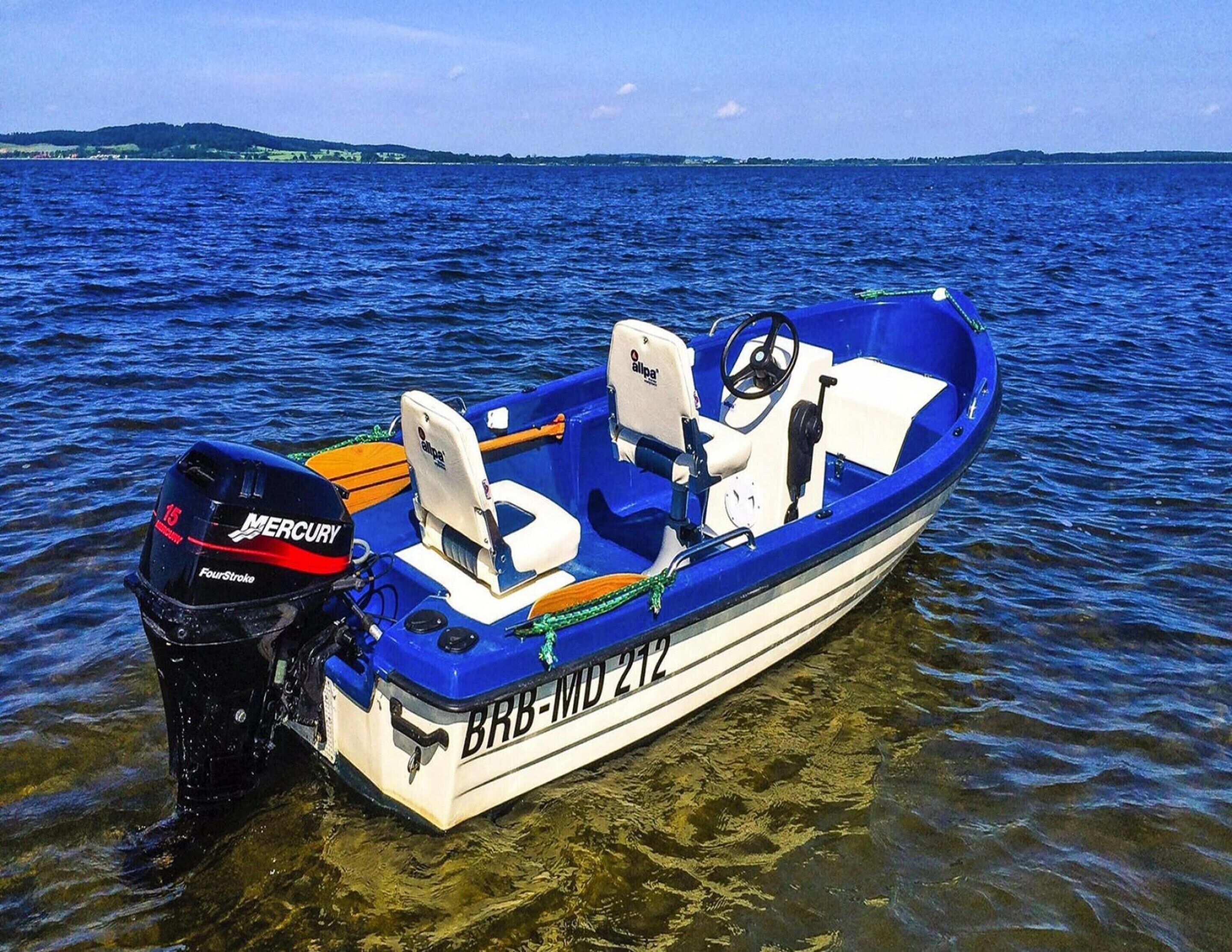 Ein kleines blau-weißes Motorboot mit einem Mercury Außenborder, gekennzeichnet mit BRB-MD 212, auf ruhigem Wasser.